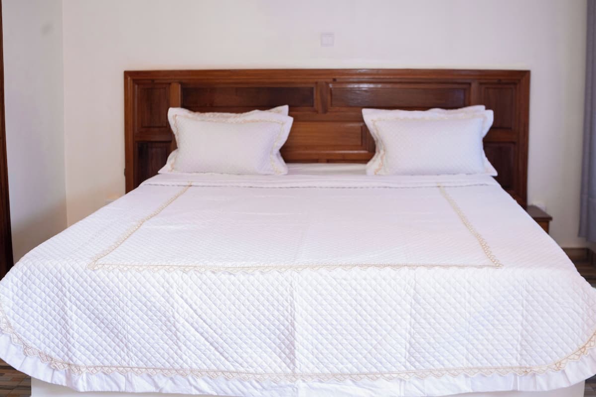A large bed with a wooden headboard and two pillows.