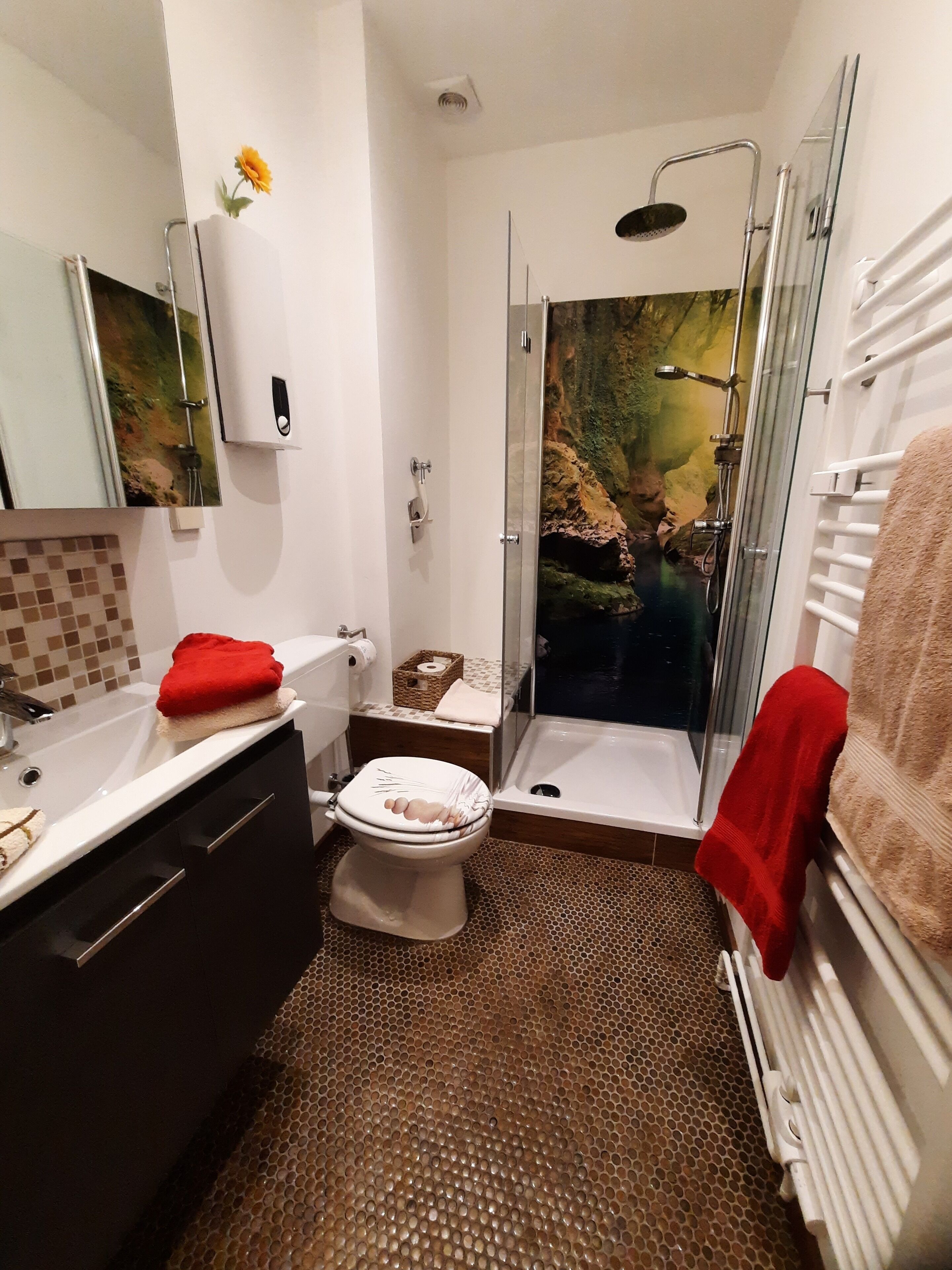 Ein Badezimmer mit Dusche, Toilette, Waschbecken und Spiegel.