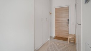 Ein Flur mit einem weißen Kleiderschrank, einer Holztür und einem kleinen Holzschemel.