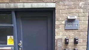Una porta nera con un cartello sopra che riporta la scritta 'Castle Mews Flats 1-4'.