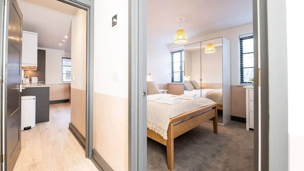 Een slaapkamer met een bed, nachtkastjes, een kledingkast en een raam met jaloezieën.