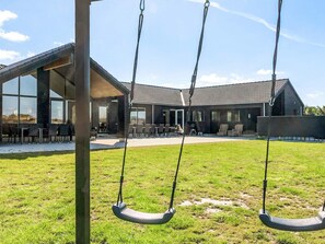 A modern building with large windows and a patio area with outdoor seating. - 5 Star Holiday Home in Idestrup (Idestrup)