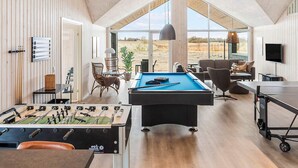 A spacious room with a pool table, foosball table, and a large window offering a view of the outdoors. - 5 Star Holiday Home in Idestrup (Idestrup)