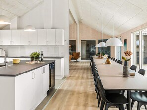 A modern kitchen with white cabinets, a central island, and pendant lighting. - 5 Star Holiday Home in Idestrup (Idestrup)