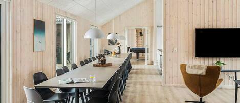A conference room with a long table, chairs, a pool table, and a television.