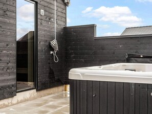 A modern outdoor bathroom with a hot tub, wooden walls, and a glass door. - 5 Star Holiday Home in Idestrup (Idestrup)