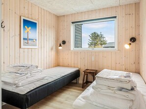 Una habitación con dos camas, una ventana con vistas y un cuadro en la pared.