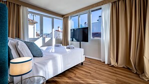 Une chambre d’hôtel avec un lit, une télévision et de grandes fenêtres équipées de rideaux.