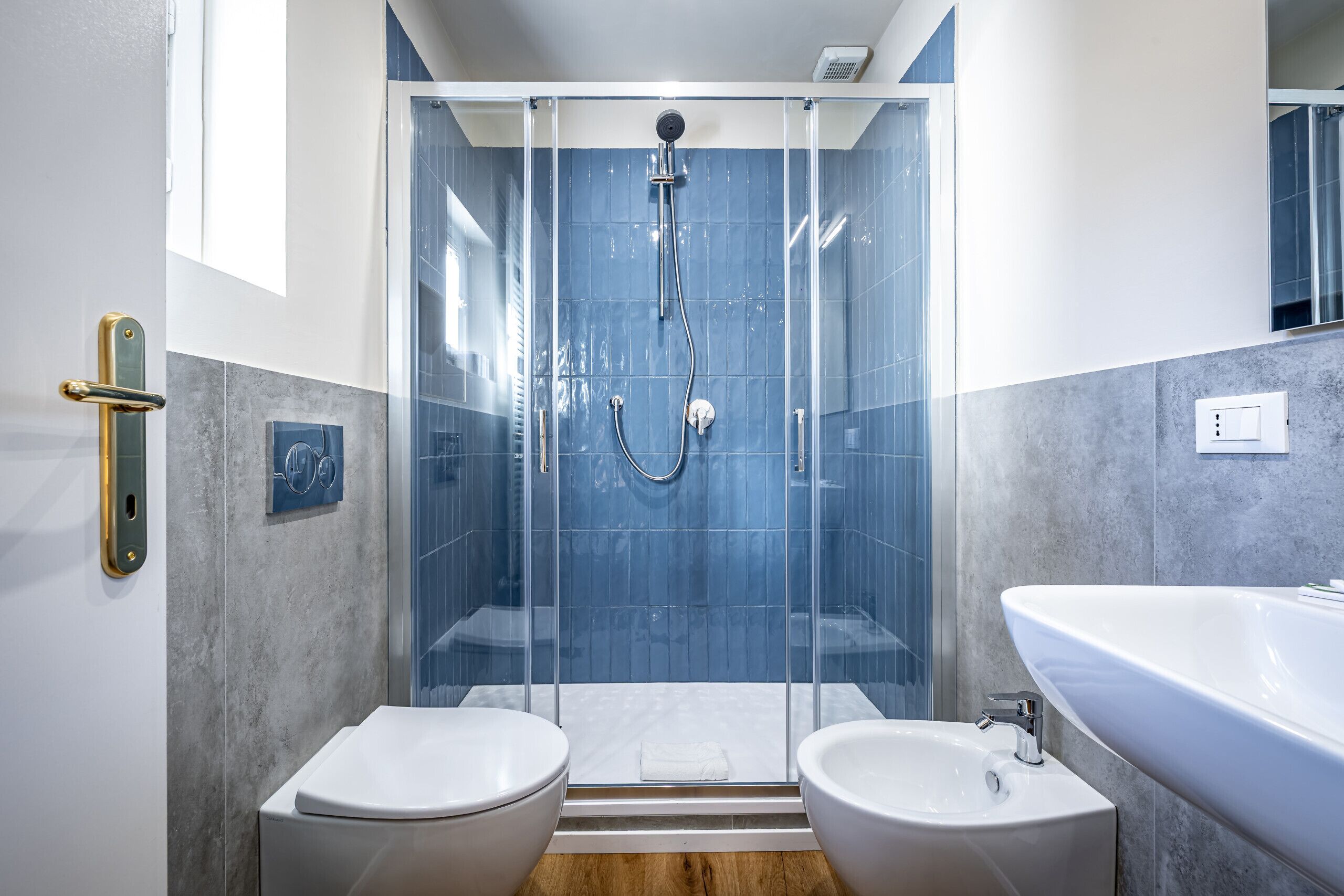 A modern bathroom with a glass-enclosed shower, two sinks, and a large bathtub.