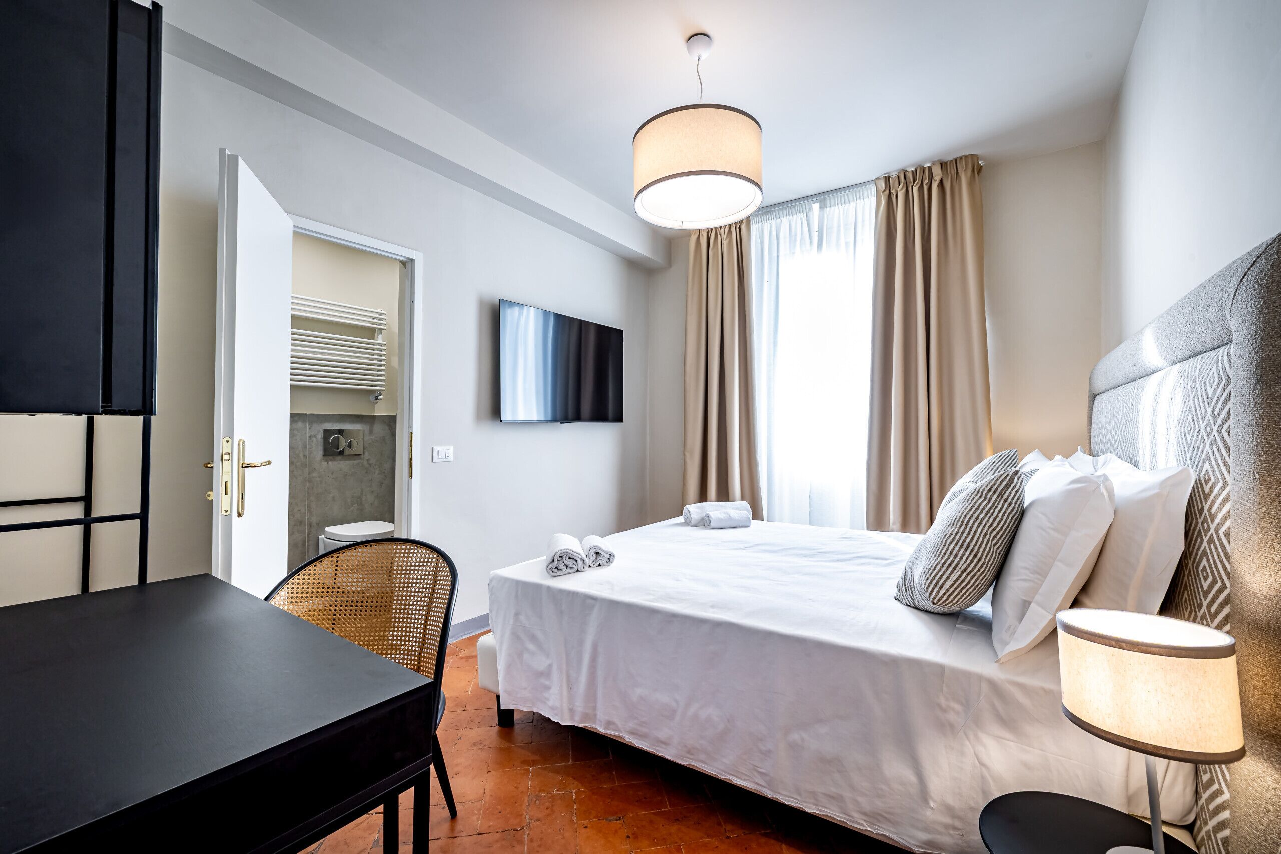 Une chambre d’hôtel avec un lit, une télévision, un bureau et une chaise.