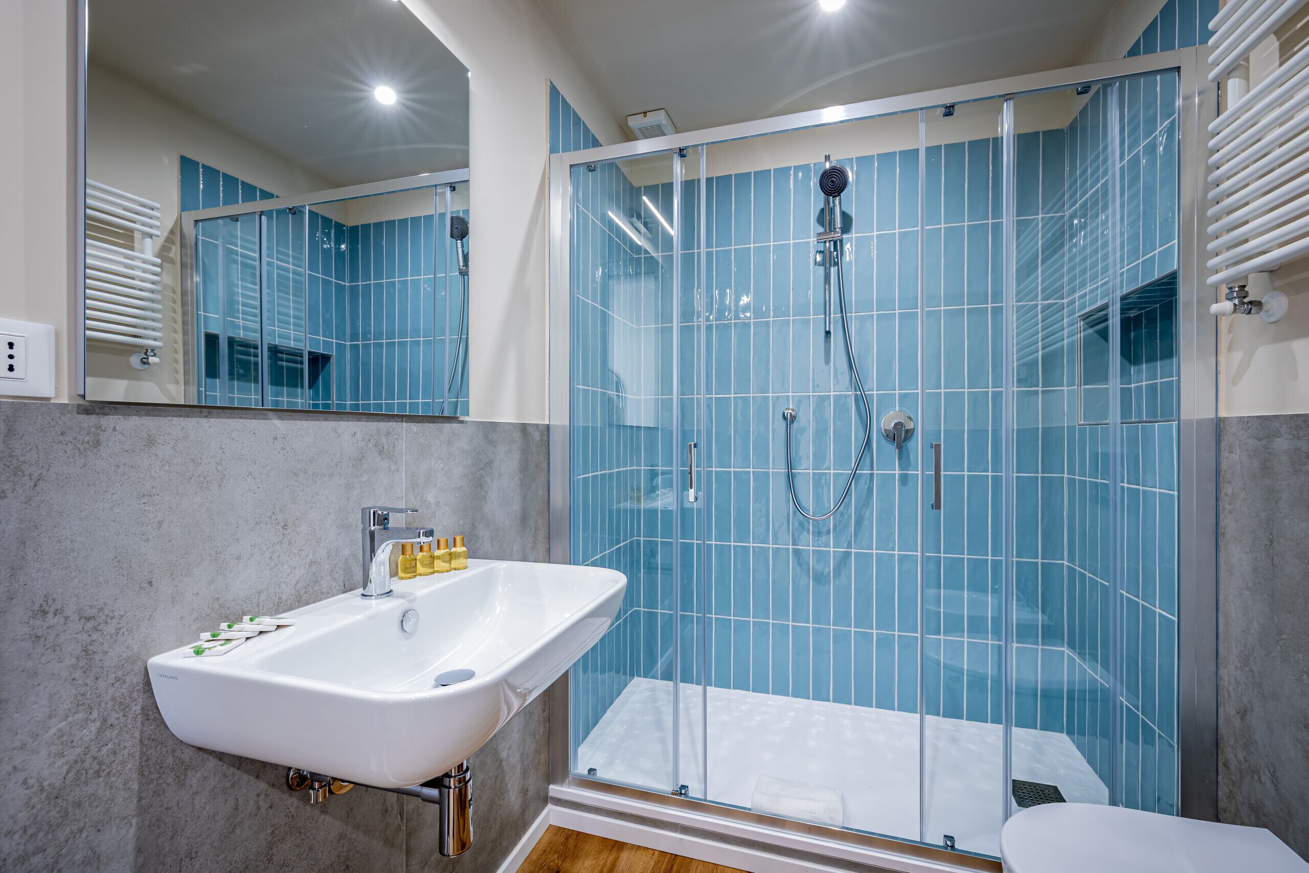 Ein modernes Badezimmer mit einer gläsernen Dusche, einem weißen Waschbecken und einem großen Spiegel.