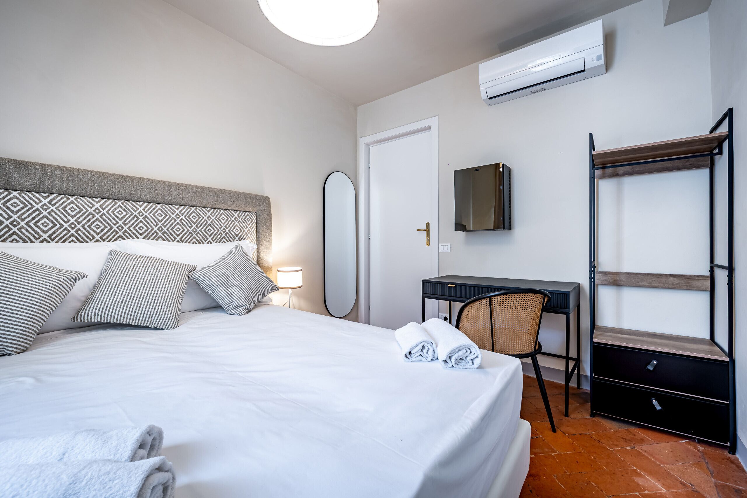 A hotel room with a bed, desk, chair, and a wardrobe.