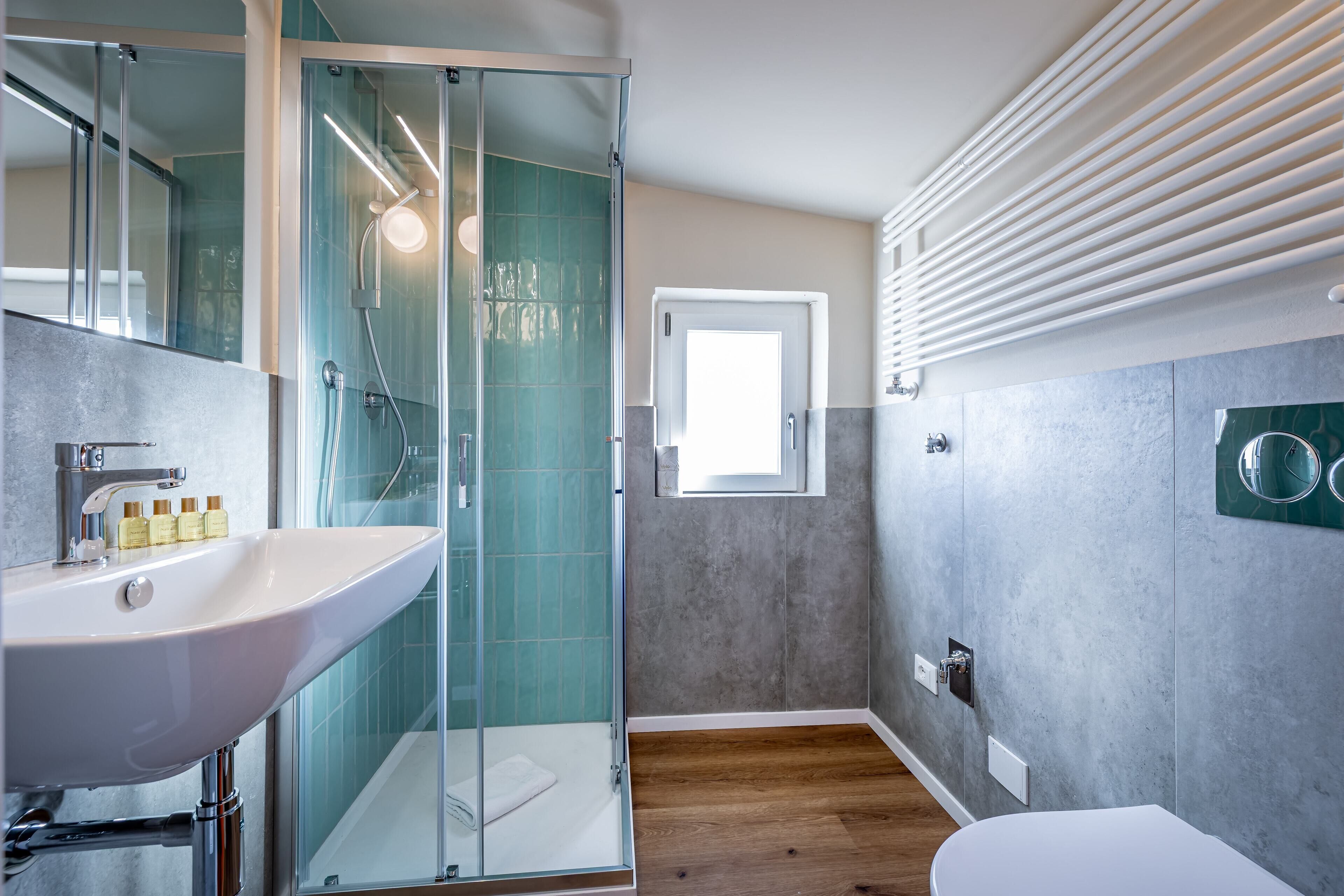 A modern bathroom with a glass shower enclosure, a white sink, and a toilet.