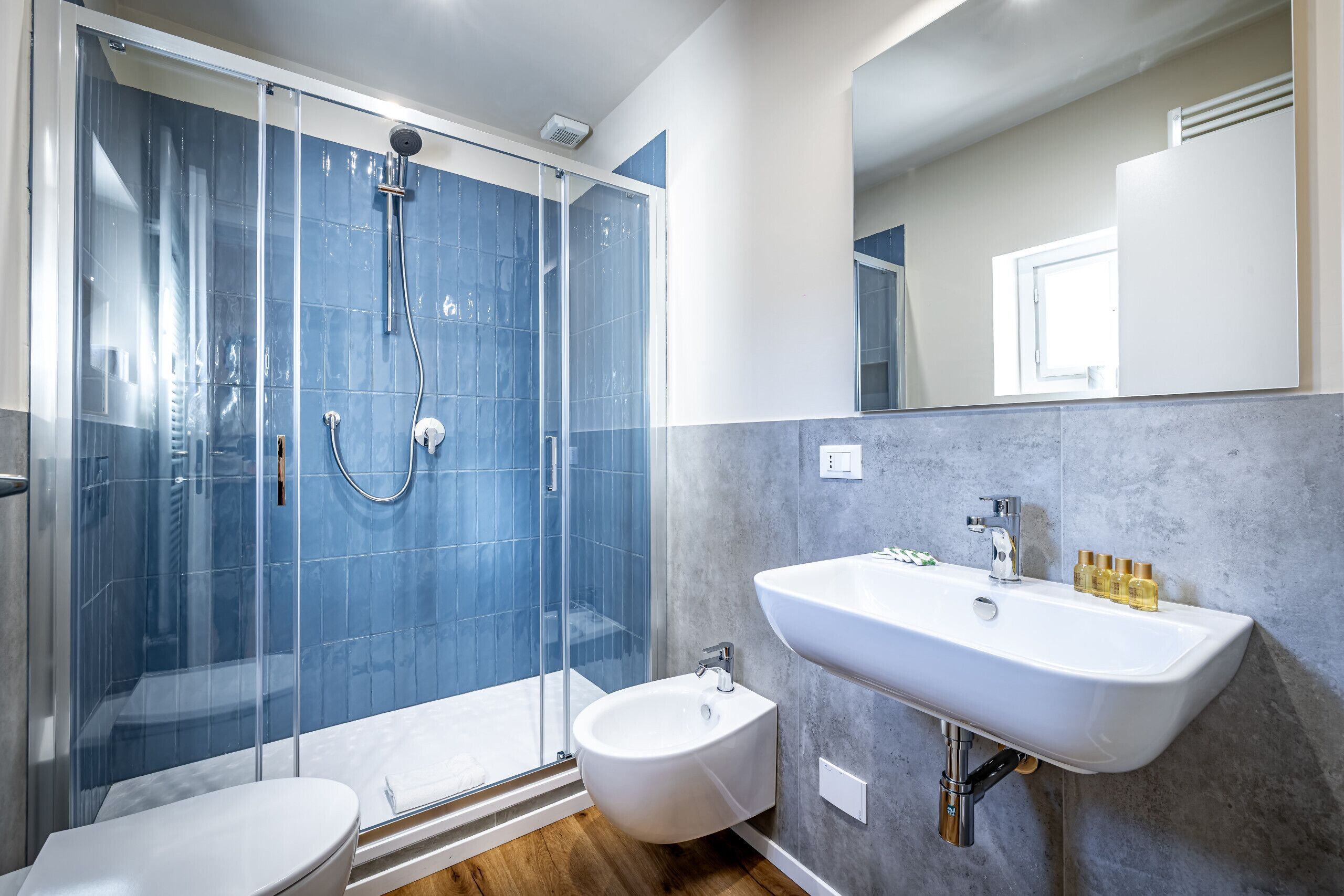 A modern bathroom with a glass-enclosed shower, a white sink, and a bidet.