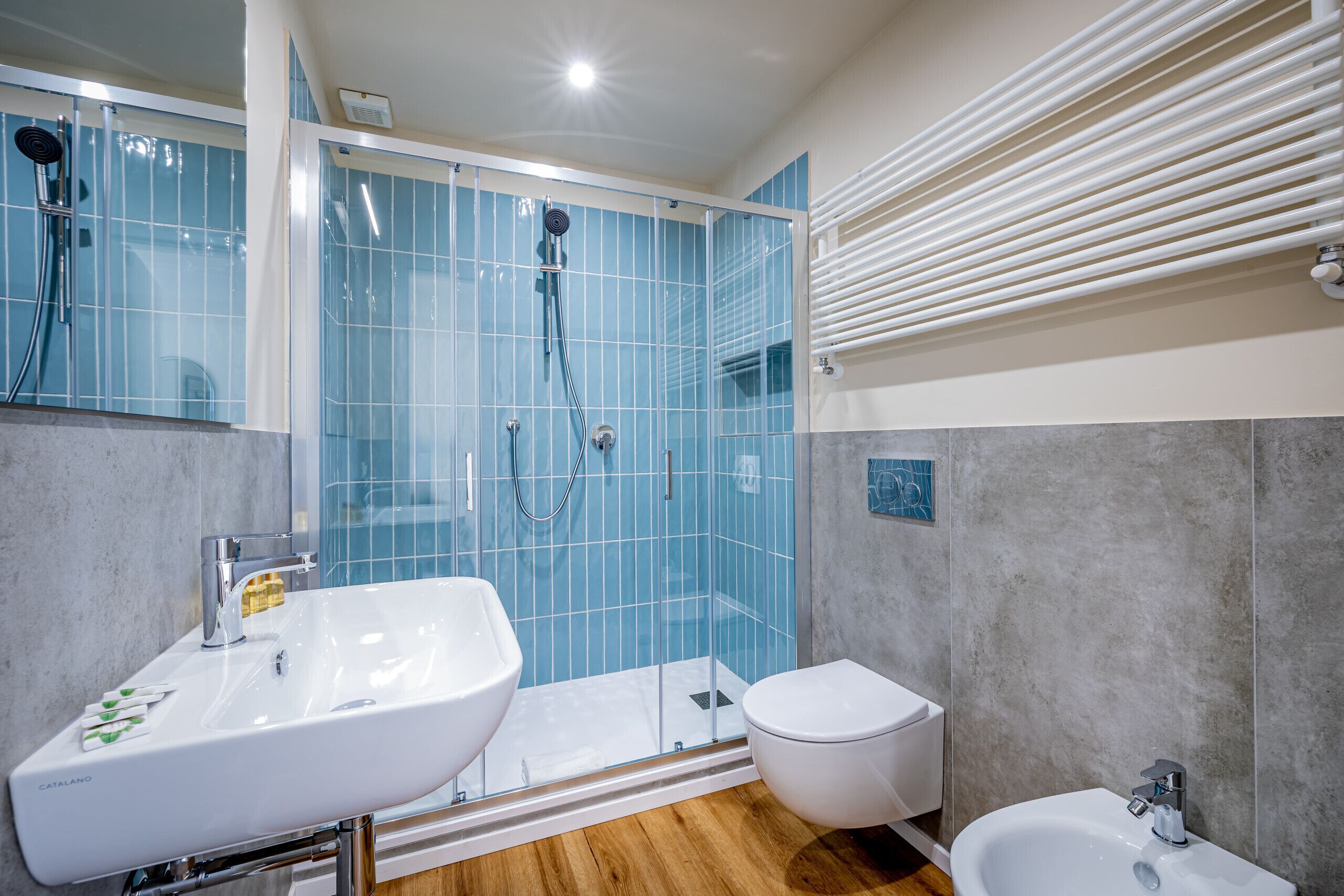 A modern bathroom with a glass shower enclosure, a double sink, a toilet, and a bathtub.