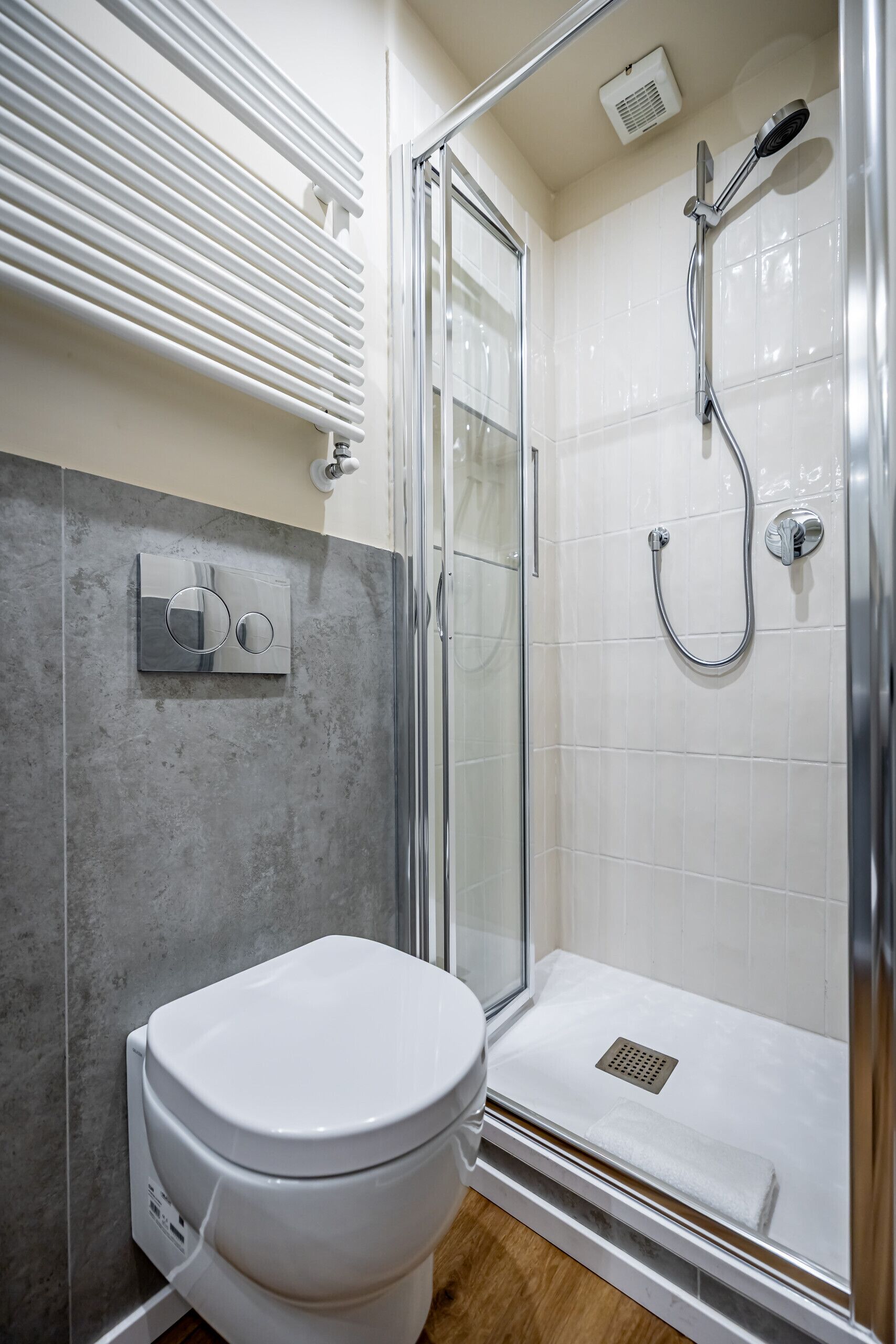 A bathroom with a shower, toilet, and a control panel.