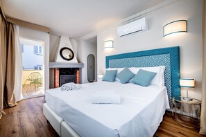 Habitación de hotel con cama, chimenea, balcón y vistas a la ciudad.