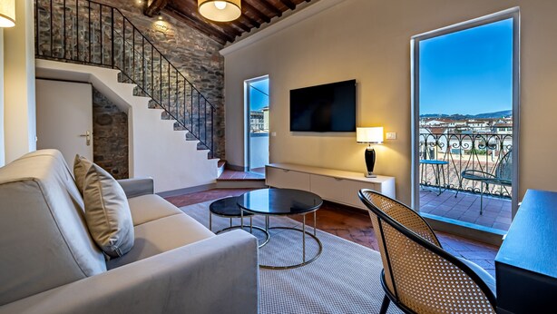 Un salon moderne avec un escalier, un canapé, une table basse et une vue sur la ville.