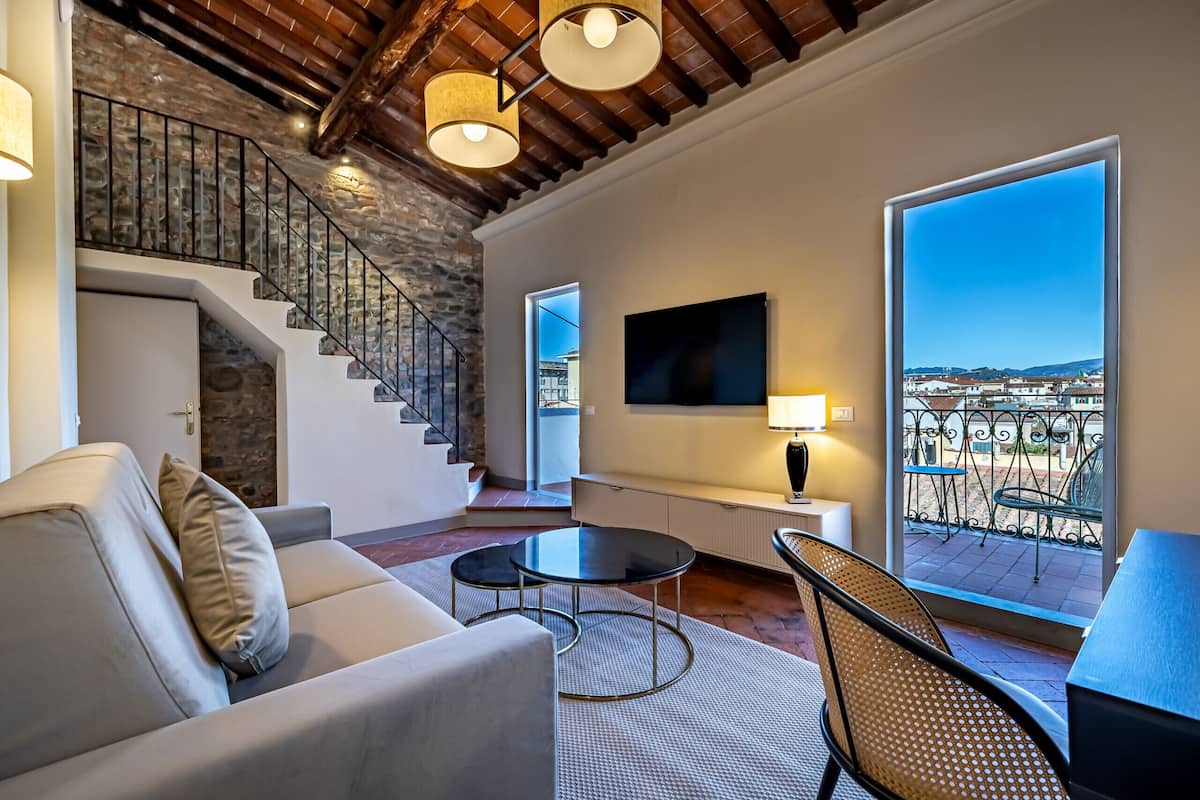 A modern living room with a staircase, a sofa, a coffee table, and a view of the city.