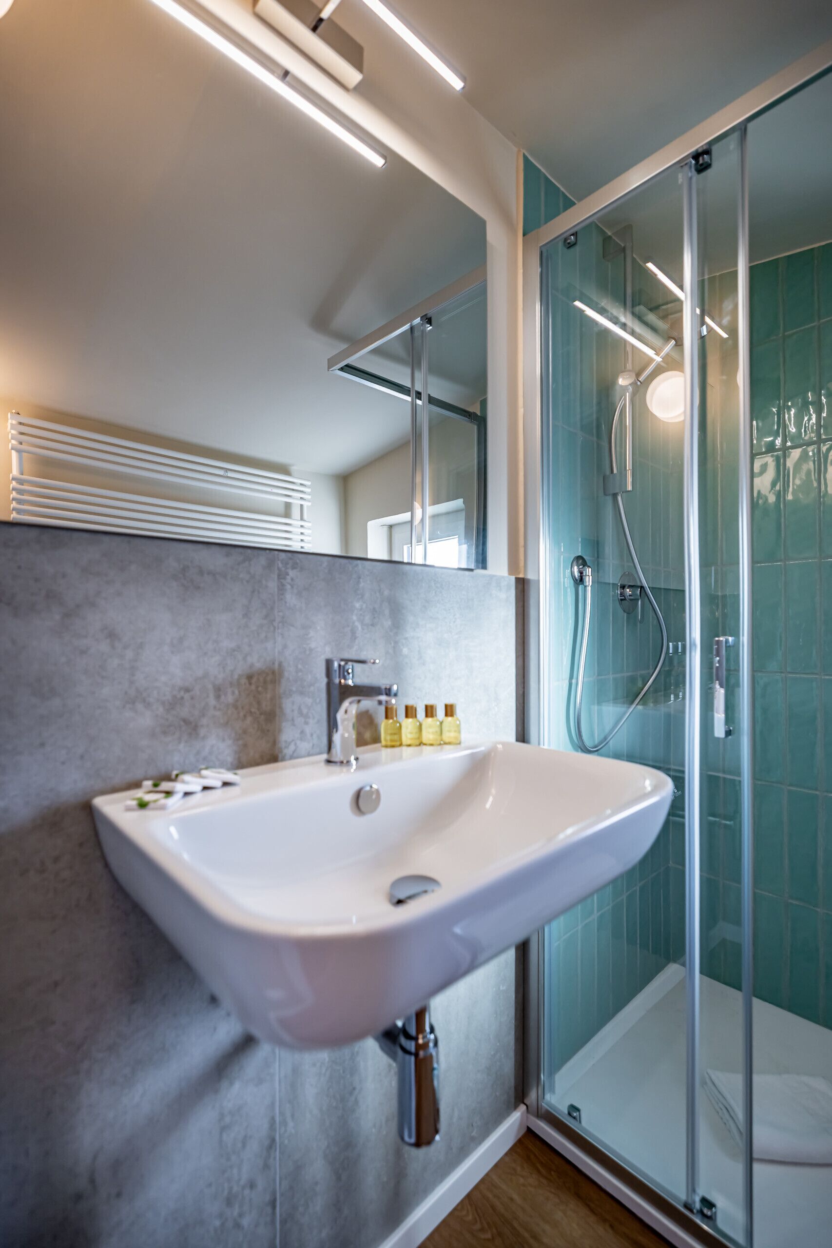 A modern bathroom with a white sink, glass shower enclosure, and a mirror above the sink.