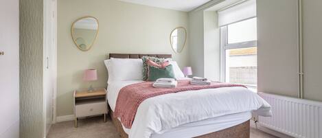 A neatly arranged bedroom with a bed, bedside tables, and a window.
