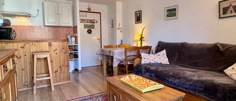 Un salon chaleureux avec un canapé marron foncé, une table basse en bois et un tapis à motifs rouges.