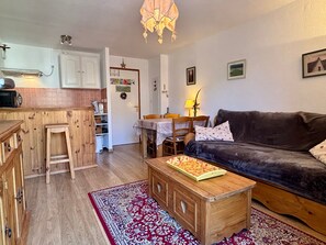 Ein gemütliches Wohnzimmer mit einem dunkelbraunen Sofa, einem Holztisch und einem roten Teppich mit Muster.