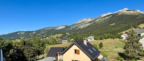 A residential area with houses, a mountain backdrop, and a clear sky.