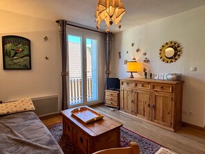 A room with a bed, a wooden cabinet, a television, and a chandelier. - Cozy 2-room apartment near ski slopes (Villard-de-Lans)