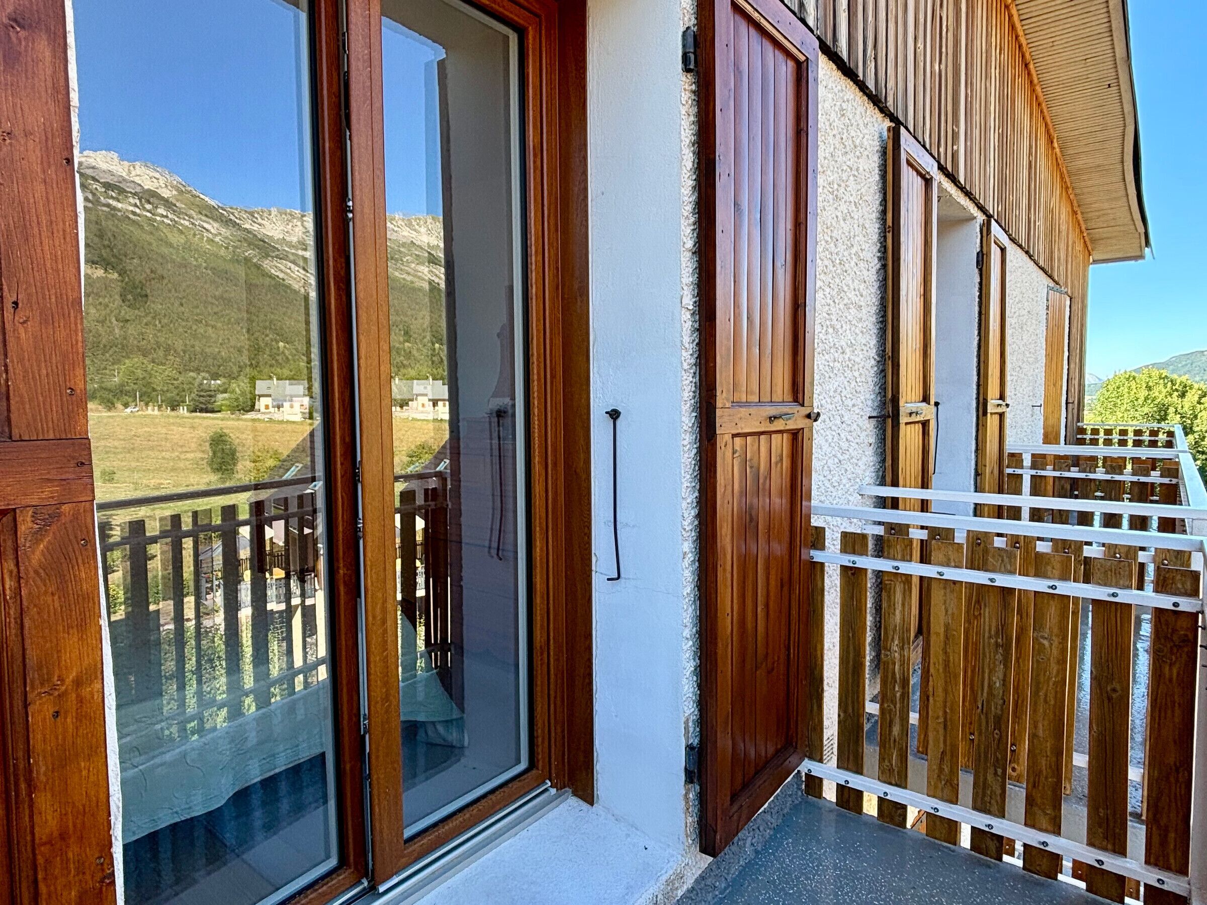 En træterrasse med en glasdør, der fører ud til en dæk, med udsigt over et bjerglandskab.