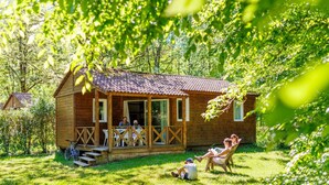 Uma cabana de madeira com varanda, rodeada por vegetação exuberante.