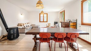 A modern kitchen with a wooden table and chairs, a built-in oven, and a window with a view of greenery. - For large gatherings: 2 apartments under a welcoming roof (Taninges)