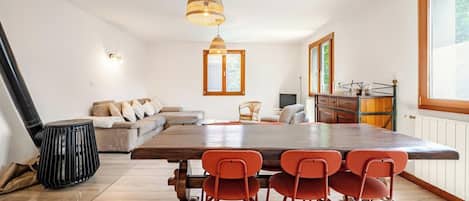 Een moderne keuken met een houten tafel en stoelen, een inbouwoven en een raam met uitzicht op groen.