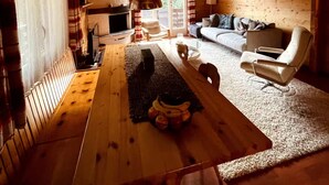 A cozy cabin interior with a wooden dining table, a sofa, and a fireplace. - Charming Swiss chalet with stunning mountain views. (Grächen)