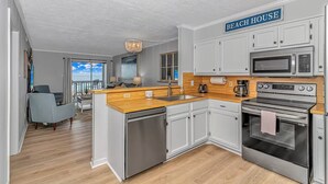 A modern kitchen with white cabinets, a wooden countertop, and stainless steel appliances. A sign above the sink reads "BEACH HOUSE." - I-2 2nd Floor Oceanfront with King Bed Suite (North Myrtle Beach)