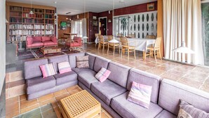 Uma sala de estar ampla com sofá modular, mesa de centro de madeira e área de refeições com mesa e cadeiras.