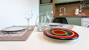 A dining table with plates, glasses, and a colorful plate. - Rated Apartment Au Clos Du Loc'h, Private Terrace with No Overlook (Pordic)