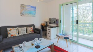 A living room with a sofa, coffee table, and a desk with a computer. - Rated Apartment Au Clos Du Loc'h, Private Terrace with No Overlook (Pordic)