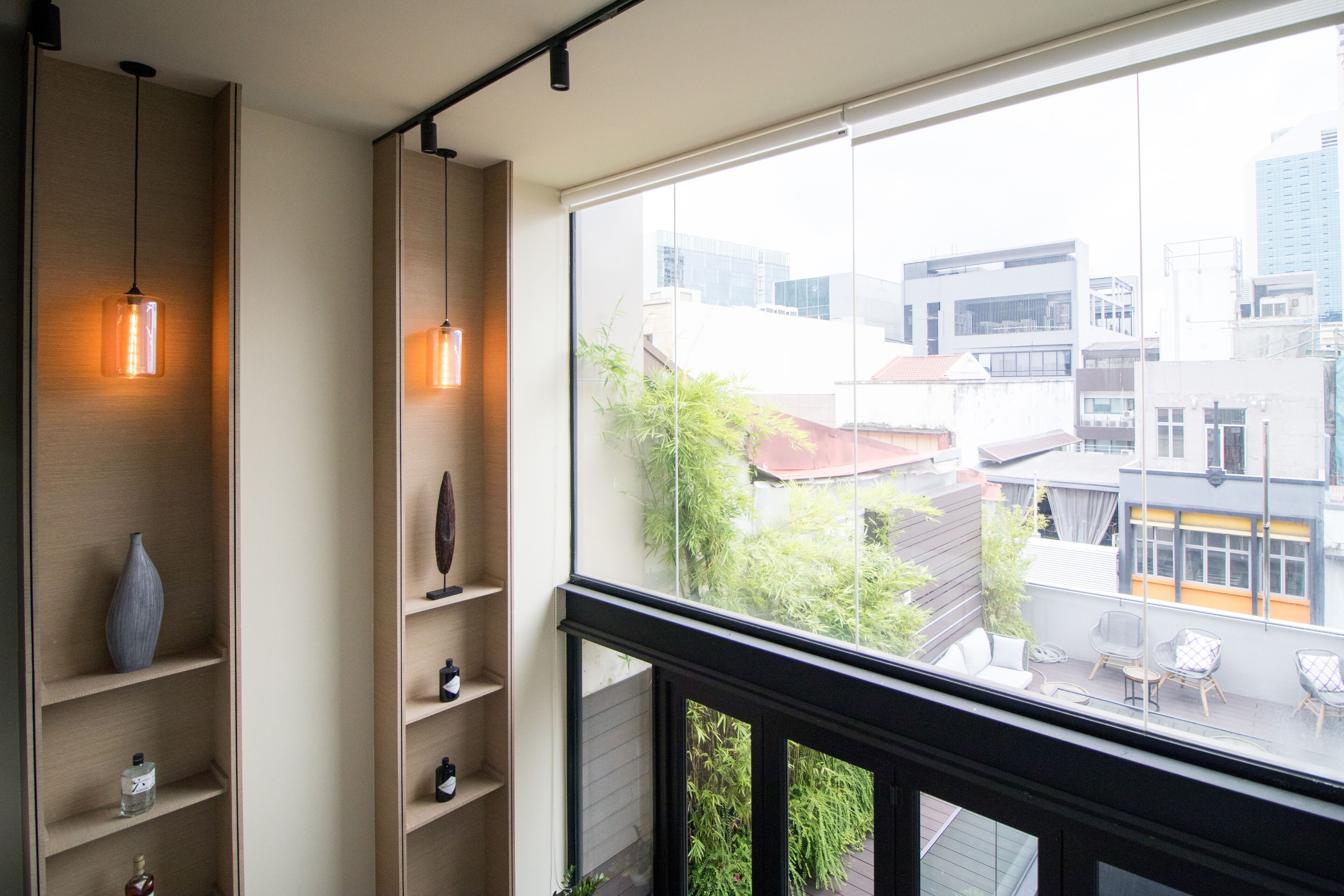 A balcony with a view of buildings, a shelf with decorative items, and a hanging light fixture.