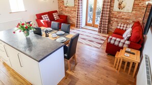 A modern living space with a kitchen area, dining table, red sofas, and a fireplace.