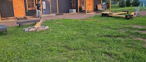 A rustic cabin with a large deck, a fire pit, and a covered outdoor seating area.