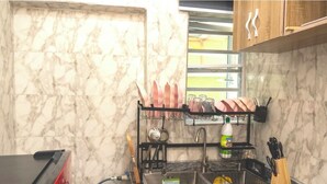 Una cocina con salpicadero de mármol, escurreplatos, fregadero y un bloque para cuchillos.