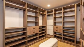 A walk-in closet with multiple wooden shelves and drawers, a bench, and a tiled floor.