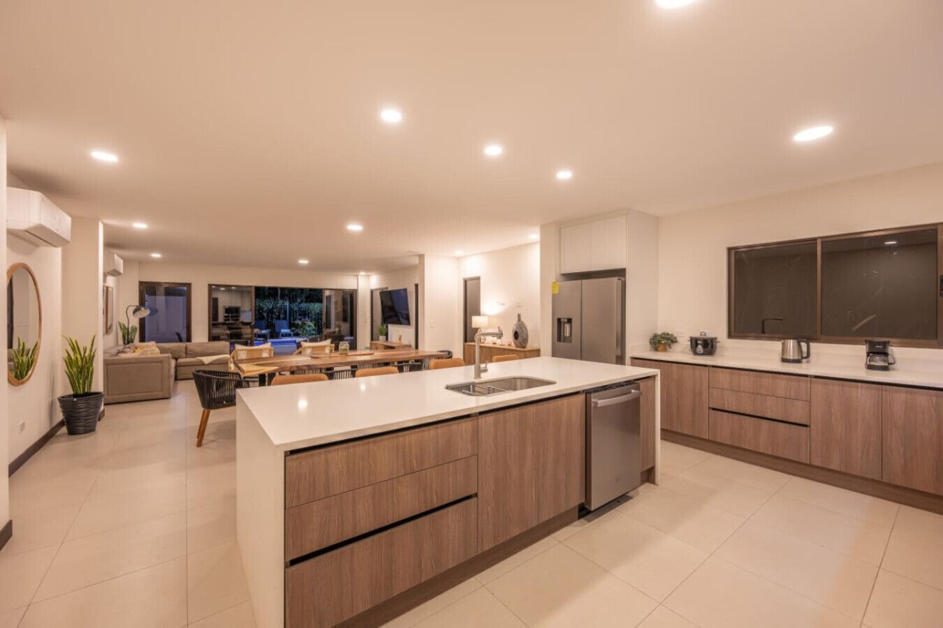 A modern kitchen with a central island, built-in appliances, and a dining area with a view of the outdoors.