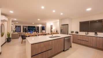 A modern kitchen with a central island, built-in appliances, and a dining area with a view of the outdoors.
