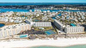 An aerial view of a coastal resort with multiple high-rise buildings, a beach, and a marina. - Remodeled Close to the Beach Islander 603 (Destin)