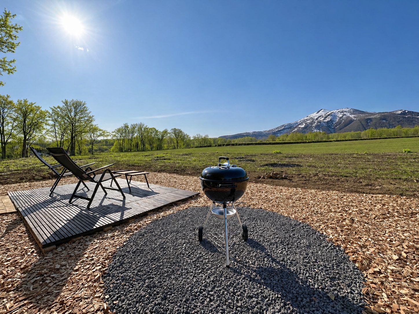A barbecue grill on a wooden deck with a view of a mountain range.