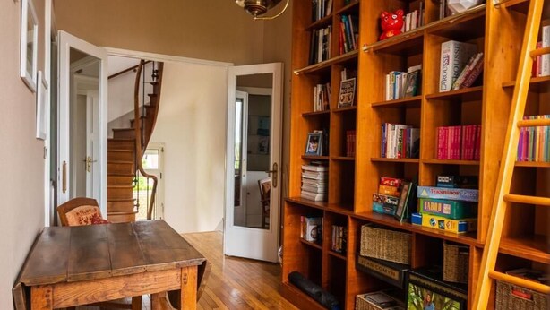 Ein Holztisch und ein Bücherregal in einem Raum mit einer Wendeltreppe.
