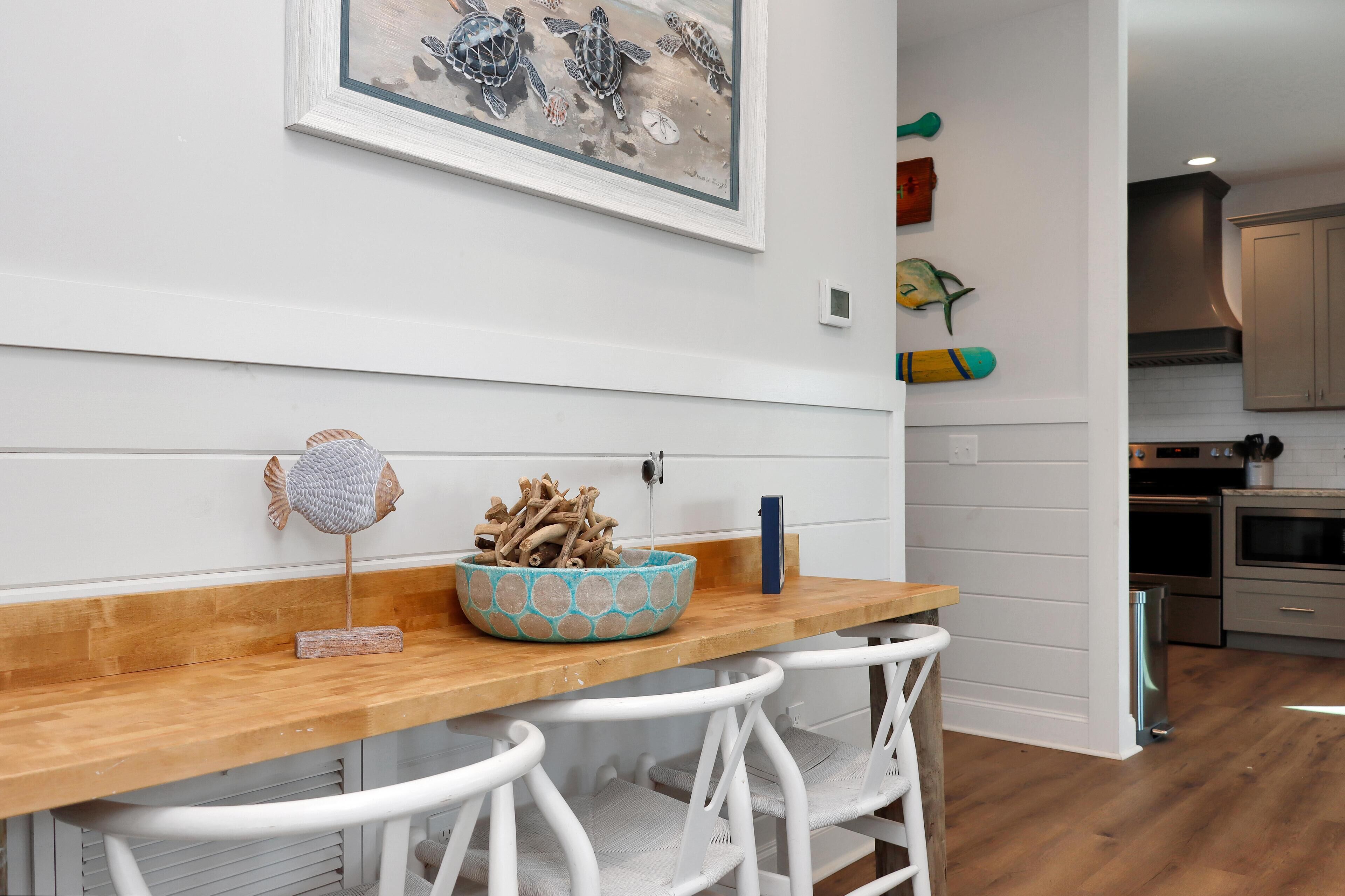 A kitchen with white cabinets, a wooden countertop, and a dining area with white chairs.