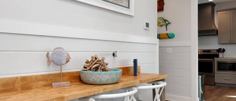 A kitchen with white cabinets, a wooden countertop, and a dining area with white chairs.